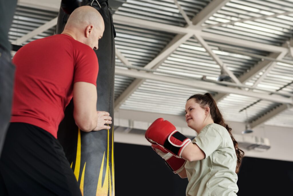 Photo of a coach teaching a young woman to hit the punch bag