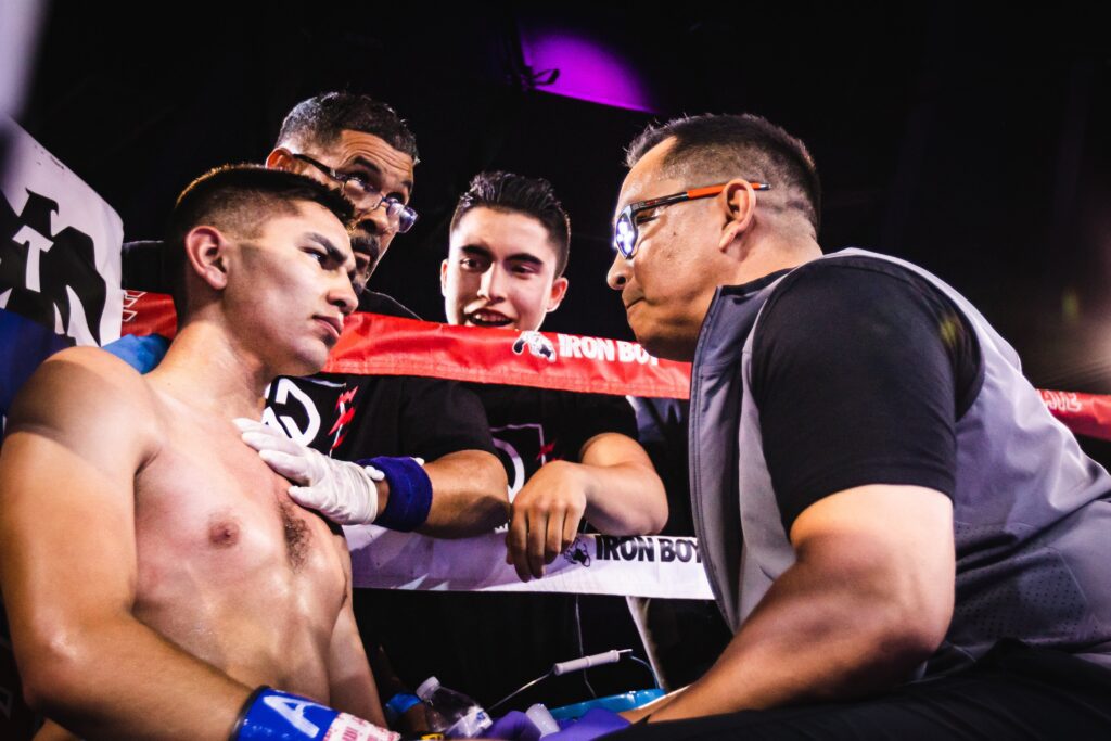 Photo of a boxing corner during a bout with the boxer receiving advice from his coaching team